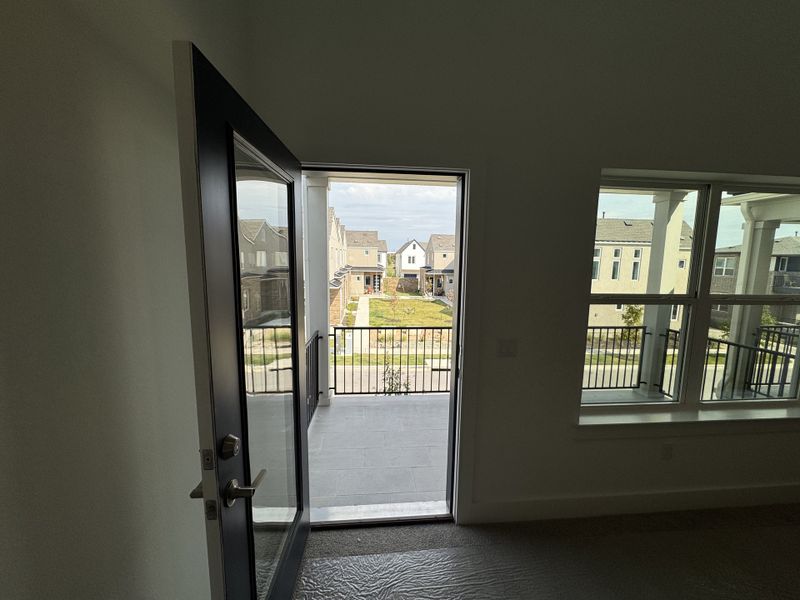 A modern balcony entrance with expansive neighborhood views, featuring sleek glass doors and stylish railing. A modern balcony entrance with expansive neighborhood views, featuring sleek glass doors and stylish railing.