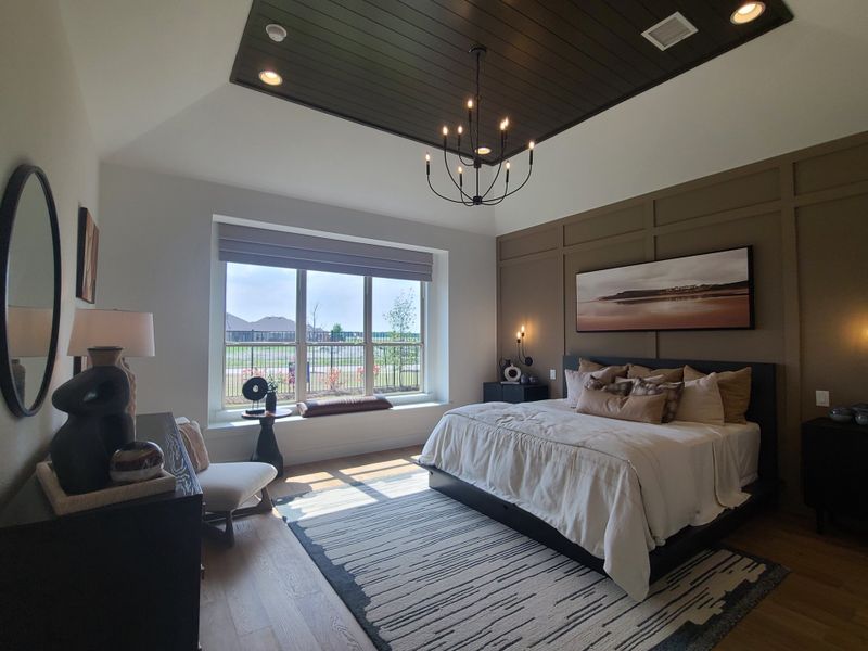 A serene bedroom with a modern chandelier, large window seating, and stylish decor elements.