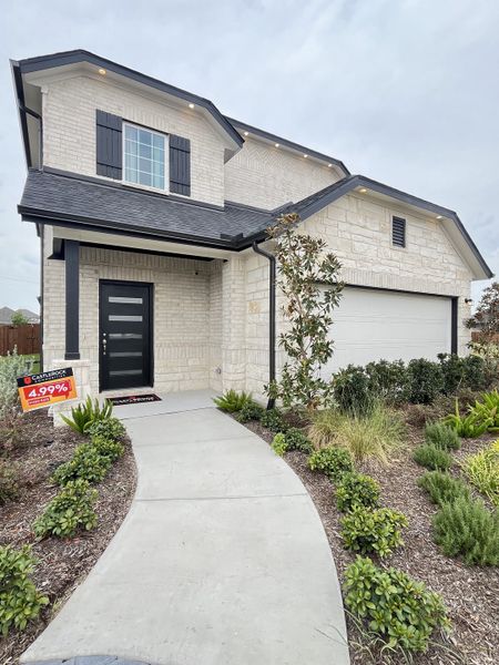 A modern white brick home with black accents and lush landscaping in Westridge by CastleRock Communities (McKinney, TX).