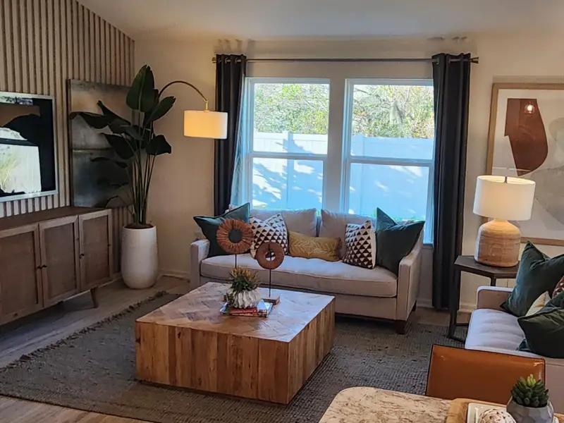 A stylish living room with warm wood tones, textured walls, and modern furnishings in Panther Creek by KB Home (Jacksonville, FL).