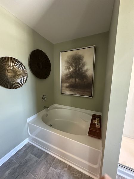 A cozy bathroom with a corner bathtub, neutral walls, and tasteful wall art.