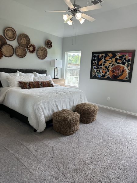 A cozy bedroom featuring a plush bed, woven decor, stylish art, and soft carpeting, creating a warm and inviting atmosphere. A cozy bedroom featuring a plush bed, woven decor, stylish art, and soft carpeting, creating a warm and inviting atmosphere.