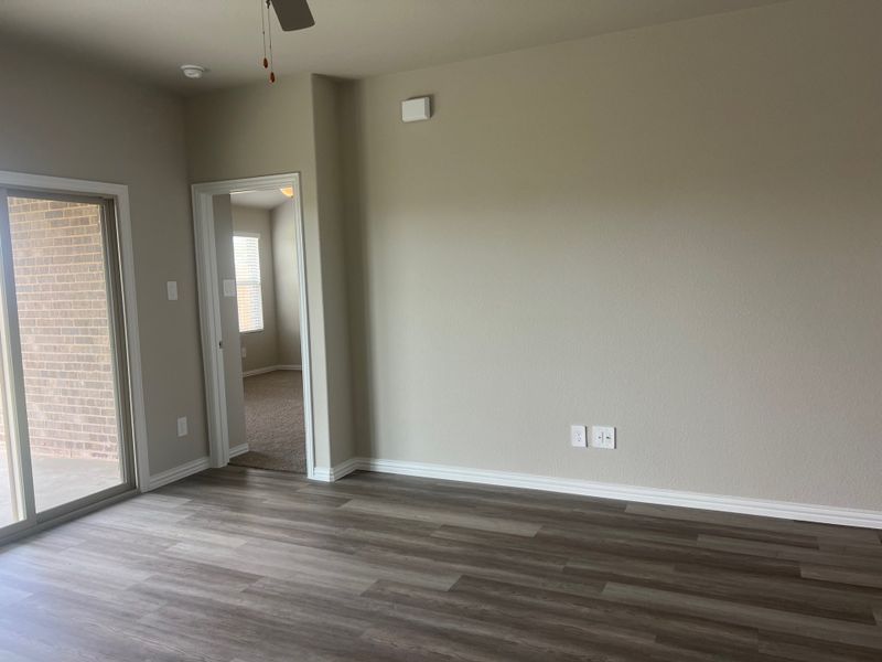 A bright room with laminate flooring, neutral walls, and sliding glass doors leading to a brick patio. A bright room with laminate flooring, neutral walls, and sliding glass doors leading to a brick patio.