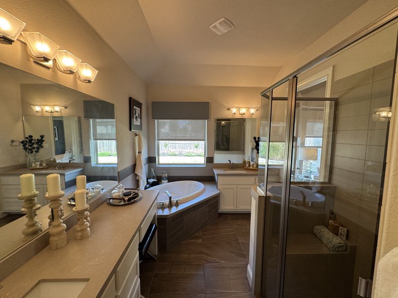 A luxurious bathroom featuring a spacious tub, glass shower, elegant lighting, and dual vanities for a relaxing retreat.