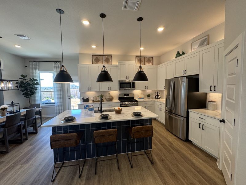 A modern kitchen featuring a sleek island, pendant lighting, and stainless steel appliances with stylish cabinetry.