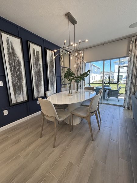 A chic dining area with bold accent walls, contemporary lighting, and an open view in Eden at Crossprairie by M/I Homes (St. Cloud, FL).