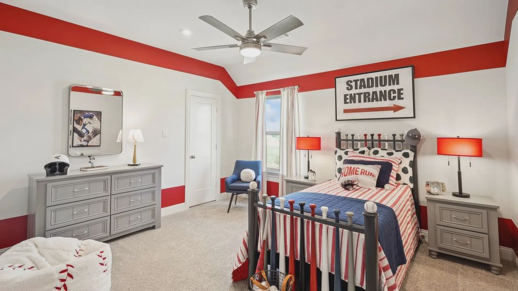 Sports-inspired bedroom with bold red decor and sleek furnishings in Ridge Crossing community. Sports-inspired bedroom with bold red decor and sleek furnishings in Ridge Crossing community.