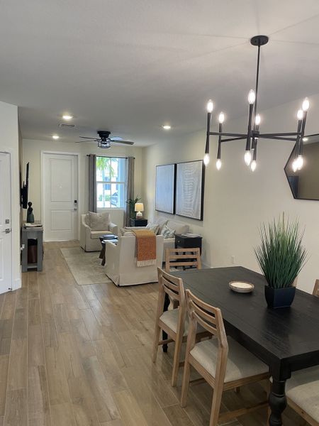 A modern living-dining space with wood flooring, elegant lighting, and cozy seating.