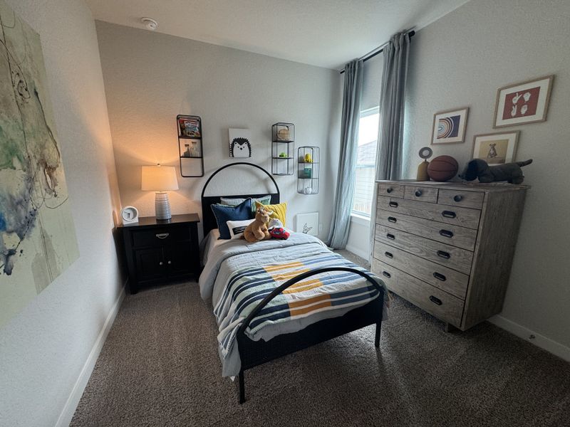 A cozy bedroom with a metal bedframe, plush carpet, and subtle art, accented by a warm lamp and modern dresser. A cozy bedroom with a metal bedframe, plush carpet, and subtle art, accented by a warm lamp and modern dresser.
