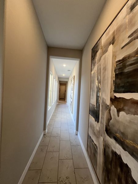 A modern hallway featuring tiled floors, neutral walls, and abstract artwork creating a stylish, inviting ambiance.
