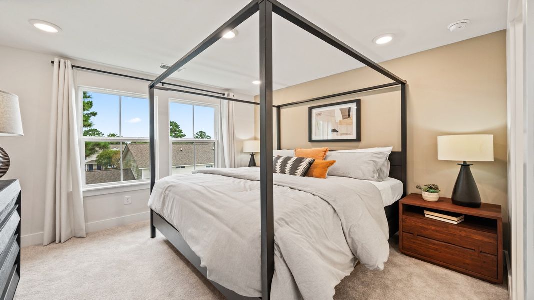 Bright primary bedroom with plush carpet and large window for abundant natural light
