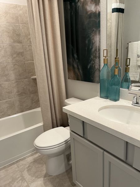 Modern bathroom featuring a sleek vanity, elegant tile work, and a stylish tub with chic accents.