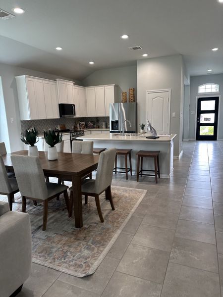 An inviting open-concept kitchen with white cabinetry, stainless appliances, and a cozy dining area with modern decor. An inviting open-concept kitchen with white cabinetry, stainless appliances, and a cozy dining area with modern decor.