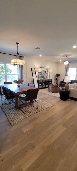 A modern living area with light wood floors, a cozy dining table, stylish seating, and elegant lighting accents.