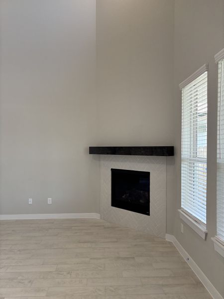 A cozy living area featuring a modern fireplace, light wood flooring, and abundant natural light. A cozy living area featuring a modern fireplace, light wood flooring, and abundant natural light.