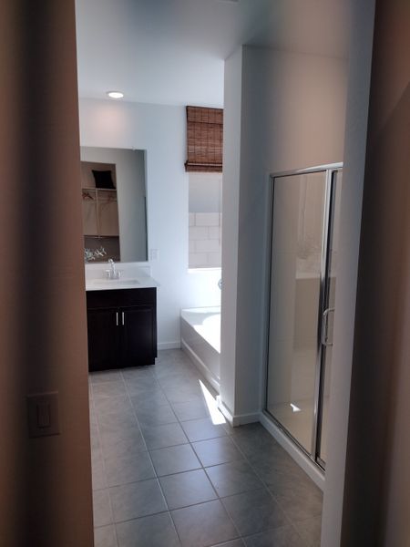 A bright bathroom featuring a sleek glass shower, dark vanity, and welcoming tiled floor. A bright bathroom featuring a sleek glass shower, dark vanity, and welcoming tiled floor.