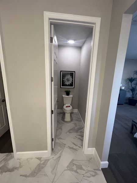 A modern powder room featuring sleek marble tile flooring, soft gray walls, and elegant framed art for a chic touch.