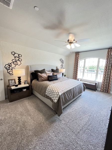 A cozy bedroom featuring a plush carpet, large window, modern decor, and elegant bedding in neutral tones. A cozy bedroom featuring a plush carpet, large window, modern decor, and elegant bedding in neutral tones.