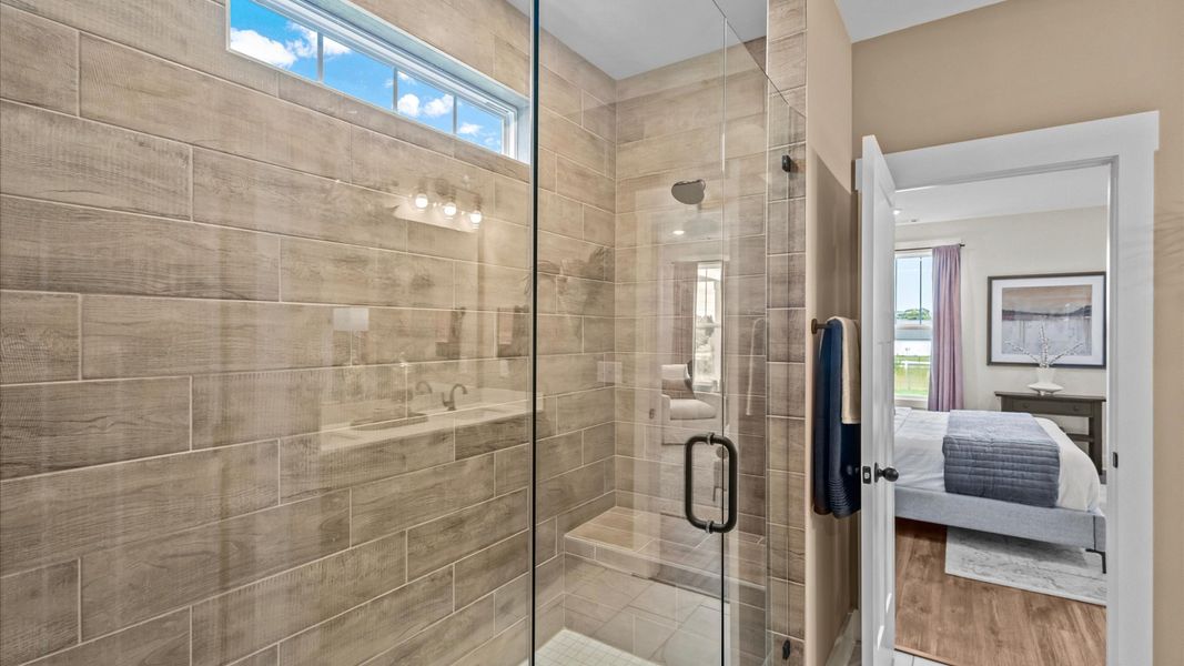En suite primary bathroom with a gorgeous frameless, tiled, walk-in Roman shower at Iris Meadows by DRB Homes in Moore, SC