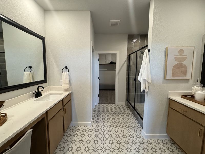 A modern bathroom with patterned tile flooring, sleek wooden cabinets, and a glass-enclosed shower. A modern bathroom with patterned tile flooring, sleek wooden cabinets, and a glass-enclosed shower.
