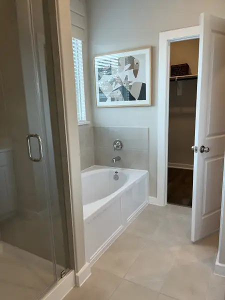 A sleek bathroom with a luxurious bathtub, framed art, and modern glass shower enclosure.