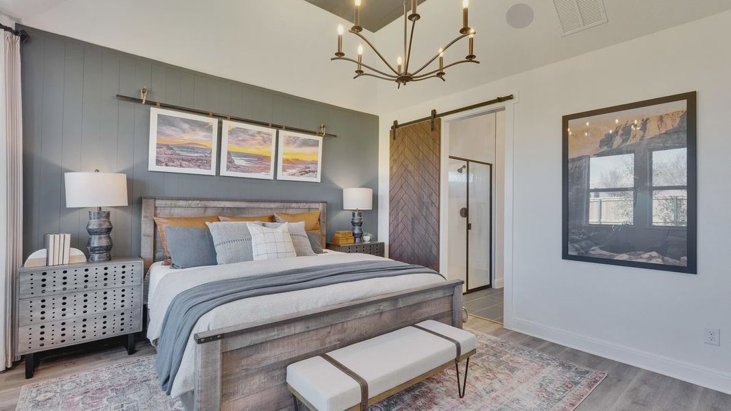 Luxurious Briarwood bedroom with rustic barn door, elegant chandelier, and large windows for natural light.