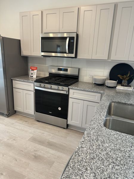 A modern kitchen with sleek gray cabinets, stainless steel appliances, and granite countertops.