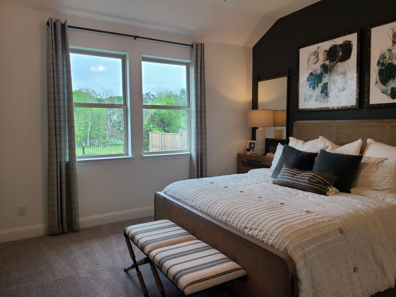 A cozy bedroom featuring a plush bed, large windows with green views, and elegant accents in neutral tones. A cozy bedroom featuring a plush bed, large windows with green views, and elegant accents in neutral tones.