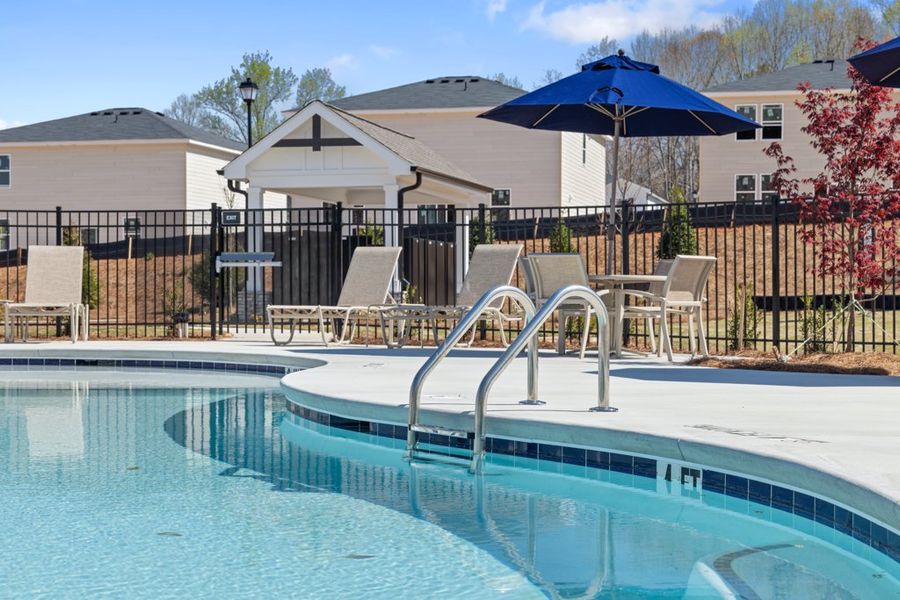 A pool with a table and chairs by it. A pool with a table and chairs by it.