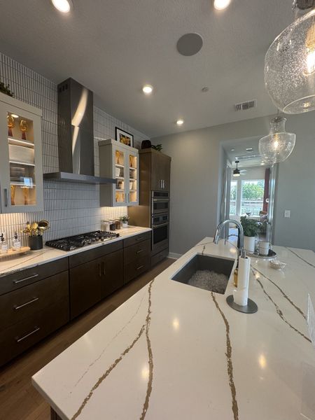 A modern kitchen featuring a sleek island with a marble-veined countertop, elegant cabinetry, and ambient lighting.