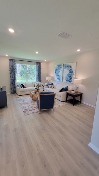 A cozy living room with elegant decor, neutral sofas, blue accents, and large window providing natural light. A cozy living room with elegant decor, neutral sofas, blue accents, and large window providing natural light.