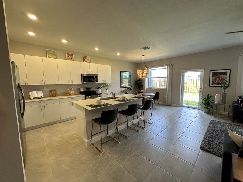 A modern kitchen with sleek cabinetry, an island with seating, and open flow to the living area. Bright and inviting space.