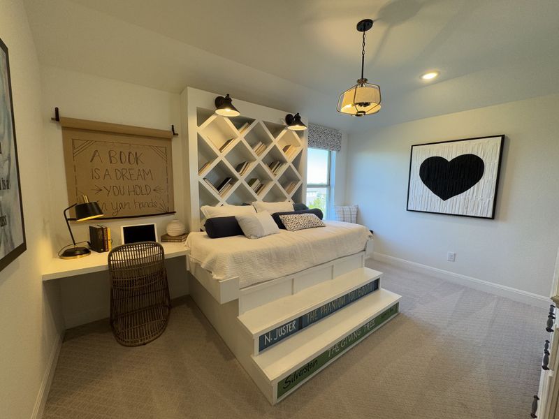 A cozy bedroom with a book-themed design, featuring a built-in desk, layered bedding, and charming wall art. A cozy bedroom with a book-themed design, featuring a built-in desk, layered bedding, and charming wall art.