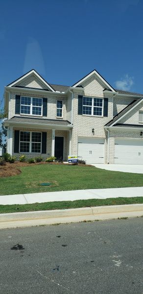 A beautiful two-story home with white brick and a manicured lawn in Butner Estates by D.R. Horton (South Fulton, GA).