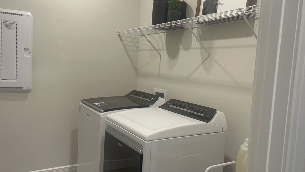 A modern laundry room with sleek appliances, open shelving, and minimalist decor.