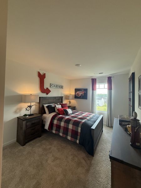 Cozy bedroom with a rustic theme, plaid bedding, automotive decor, and natural light from a large window.
