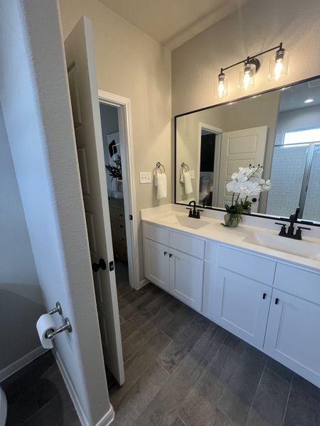 A modern bathroom with sleek white cabinetry, dual sinks, and elegant lighting. A modern bathroom with sleek white cabinetry, dual sinks, and elegant lighting.