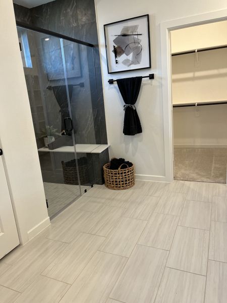 A modern bathroom with sleek tile flooring, a glass shower, abstract art, and a spacious walk-in closet. A modern bathroom with sleek tile flooring, a glass shower, abstract art, and a spacious walk-in closet.