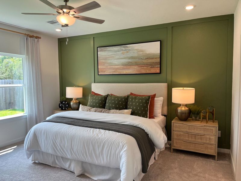 A cozy bedroom featuring an olive accent wall, elegant bedding, and warm lighting with natural wood accents.