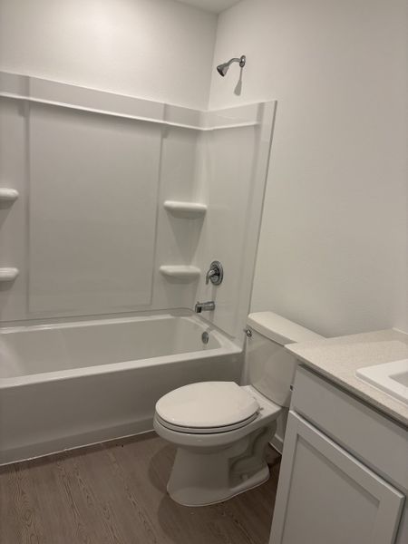 A sleek bathroom with a classic bathtub, practical shower, and modern fixtures on laminated flooring.