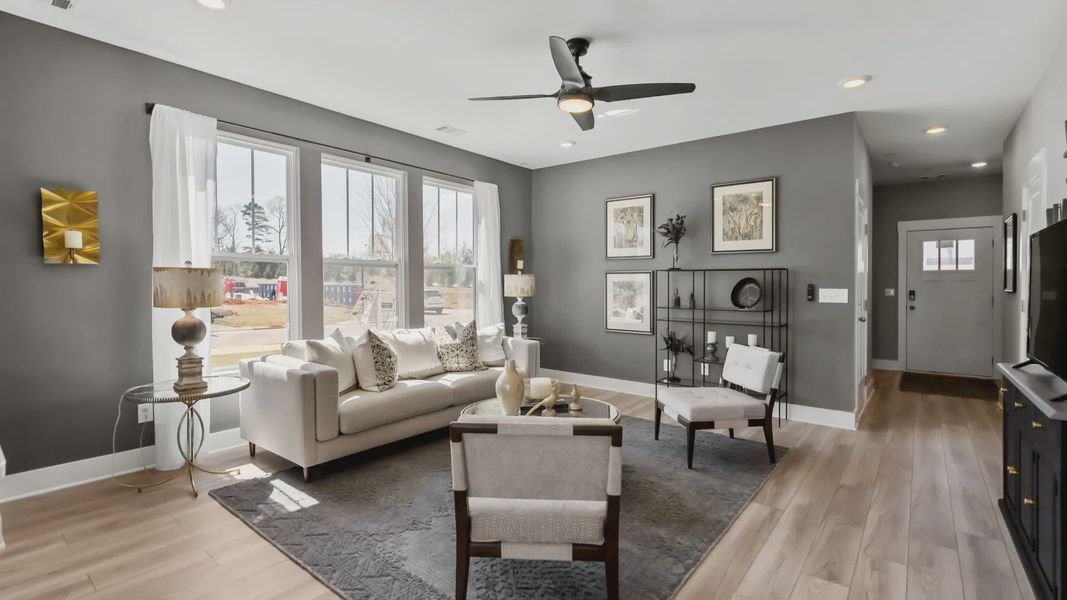 Spacious, cozy, modern family room with hardwood floors and large windows at Saluda Crossing by DRB Homes in Piedmont, SC