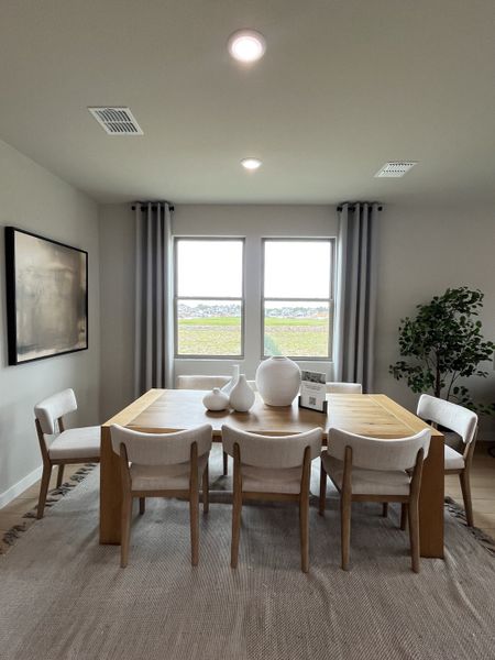 A contemporary dining area featuring a wooden table, elegant chairs, and large windows providing abundant natural light.