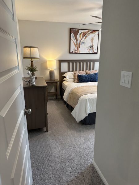 A cozy bedroom featuring a wooden bed, elegant lamps, and modern artwork, creating a warm and inviting atmosphere.