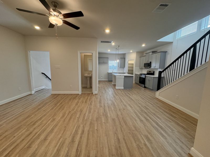 An open-concept living space with wood floors, modern kitchen, and staircase. Bright and inviting layout with ample lighting. An open-concept living space with wood floors, modern kitchen, and staircase. Bright and inviting layout with ample lighting.