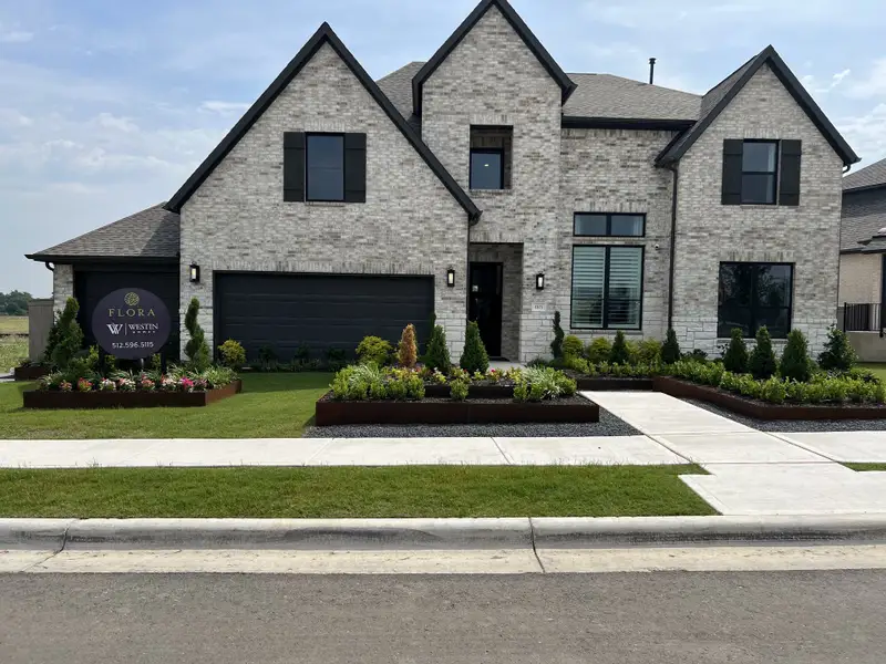 Elegant brick home with manicured landscaping in Flora - 60' by Westin Homes (Hutto, TX).