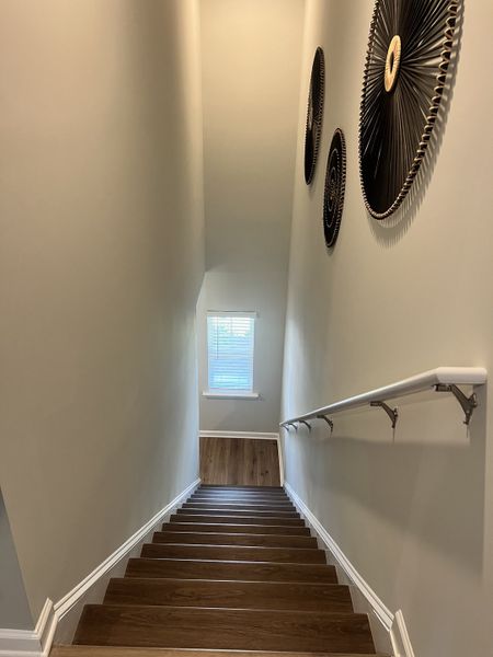 A contemporary staircase with sleek wooden steps, decorative wall art, and a small window for natural light.