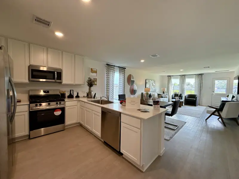 Modern open-concept kitchen and living area with white cabinetry, stainless appliances, and bright, natural lighting.