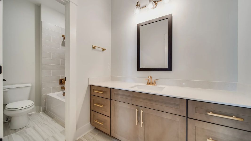 Experience luxury with a sophisticated vanity, chic gold finishes, and exquisite marble tile in Shelton Square.