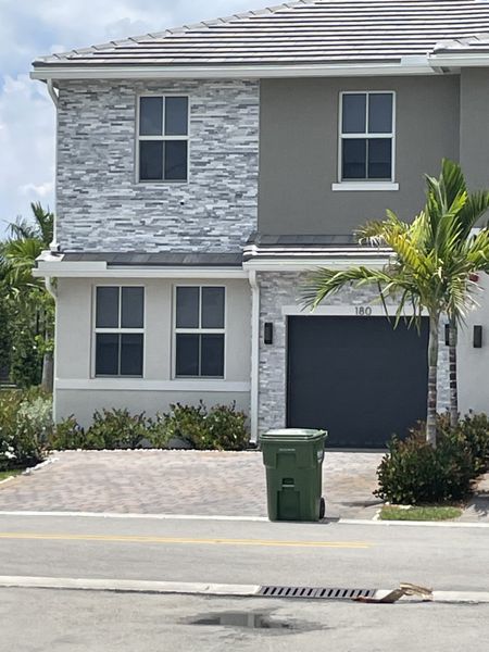 A modern two-story home with sleek stone accents and palm trees in Merrick Square by D.R. Horton (Pembroke Pines, FL).