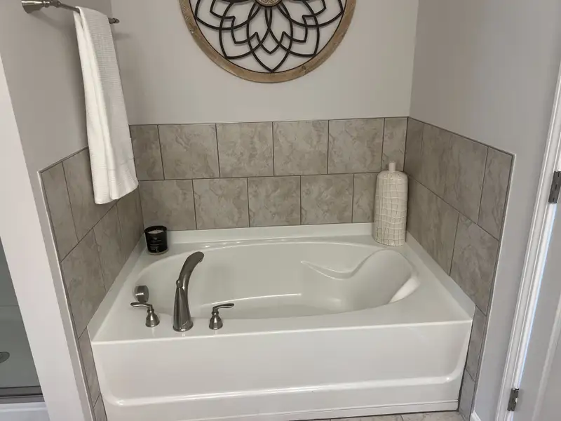 A modern bathroom features a sleek built-in bathtub, elegant tile walls, and chic decorative accents. A modern bathroom features a sleek built-in bathtub, elegant tile walls, and chic decorative accents.